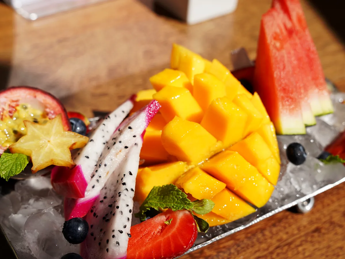 Bandeja de fruta a pleno sol con pitaya, mango, sandía, carambola y fresas sobre hielo