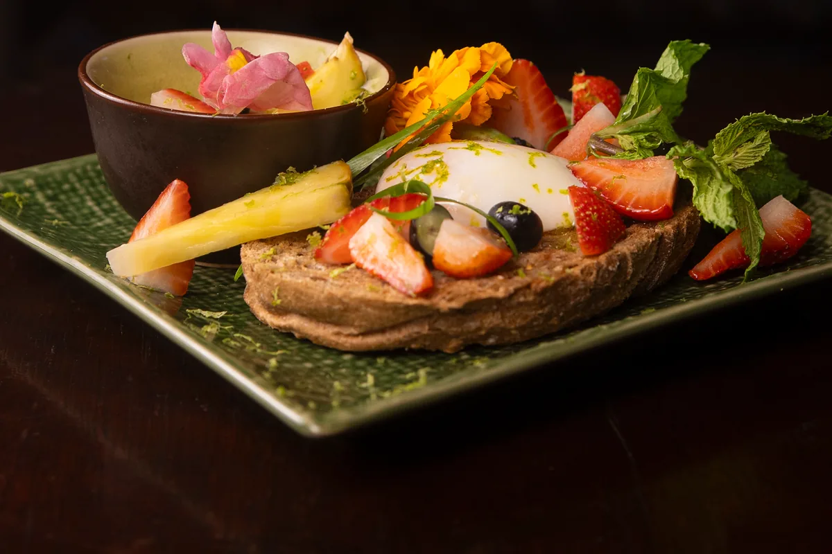 Tostada de masa madre con huevo a baja temperatura, fresas, arándanos, piña, menta y un cuenco de kaya de coco y pandan